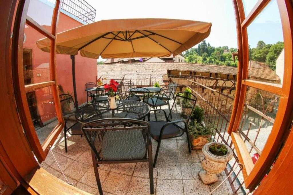 Shared terrace with tables and a parasol at Mini Apart Hotel Abraka